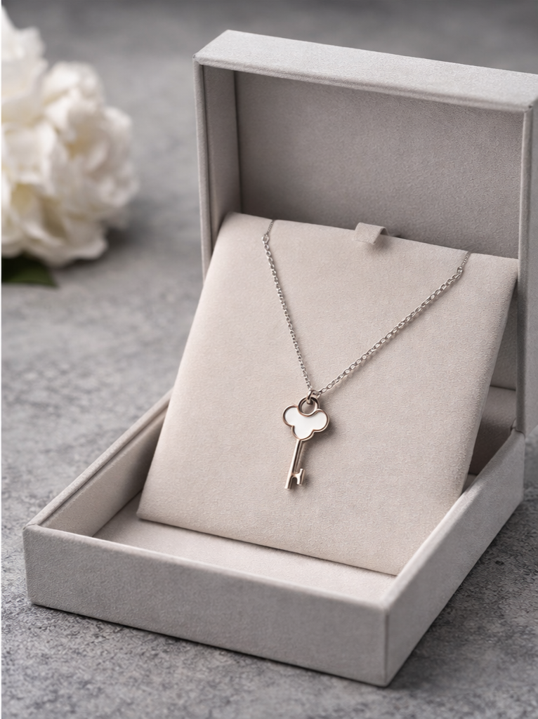 Silver key necklace in an open jewelry box with white flowers in the background