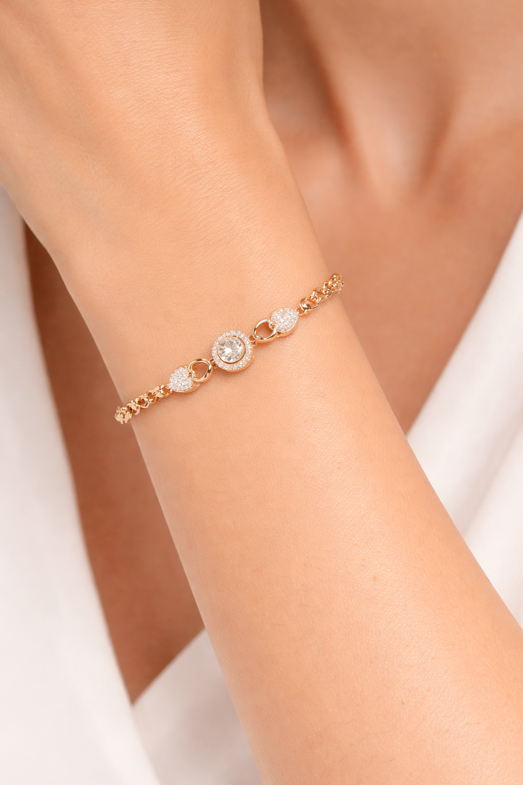 Rose gold bracelet with gemstones on a wrist against a white background