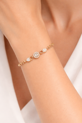Rose gold bracelet with gemstones on a wrist against a white background