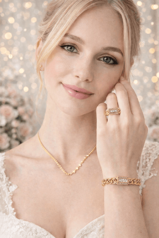 Woman wearing gold jewelry with a blurred floral background