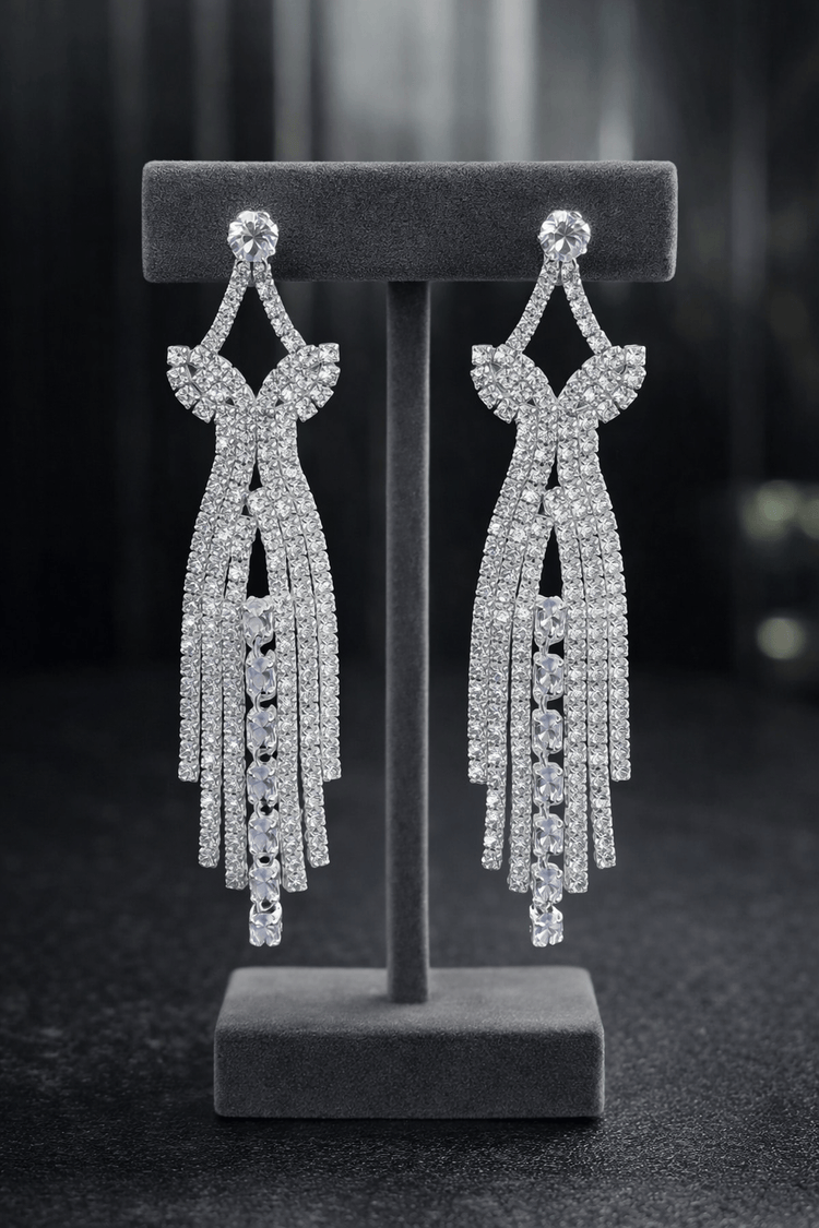 Pair of silver earrings on a gray stand against a dark background