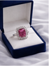 Ring with a pink gemstone in a blue velvet box on a white fabric background