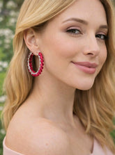Woman wearing red hoop earrings with a blurred green background