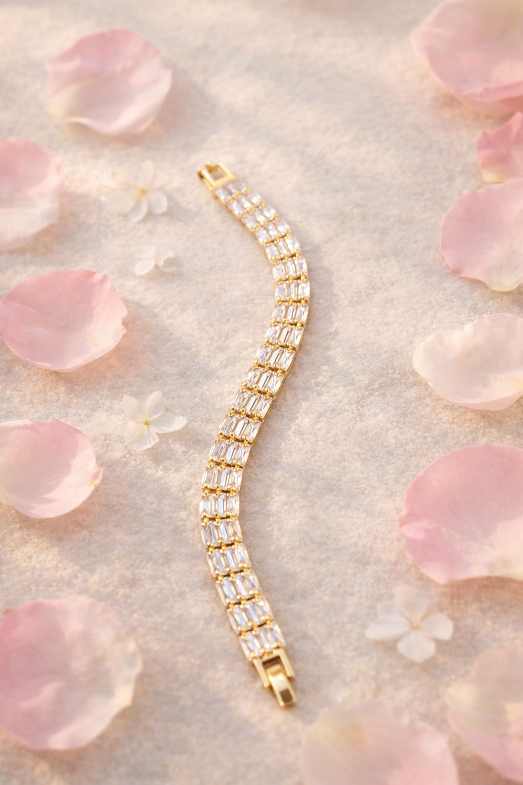 Gold bracelet with clear stones on a soft pink floral background