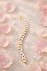 Gold bracelet with clear stones on a soft pink floral background