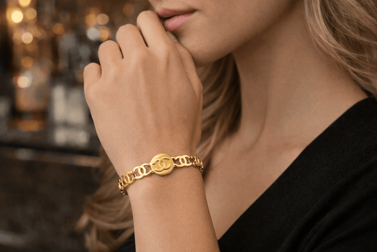Close-up of a person wearing a gold bracelet with a blurred background