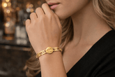 Close-up of a person wearing a gold bracelet with a blurred background