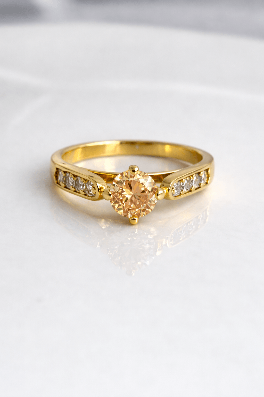 Gold ring with a heart-shaped diamond on a light background