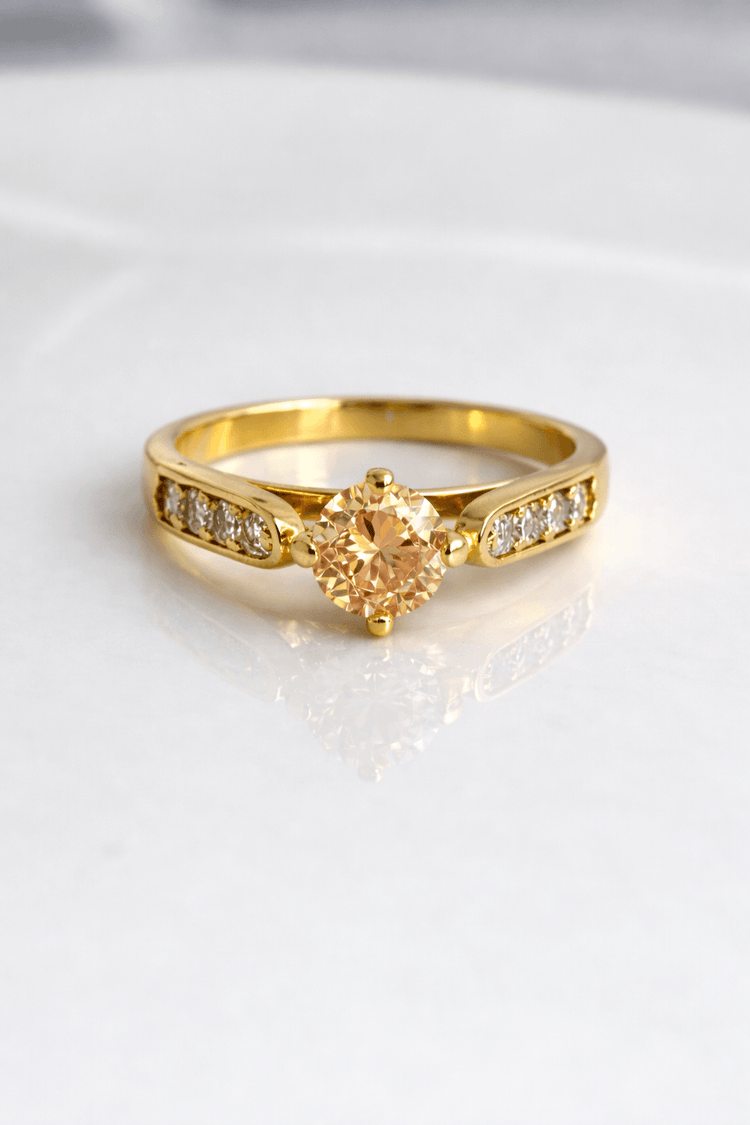 Gold ring with a heart-shaped diamond on a light background