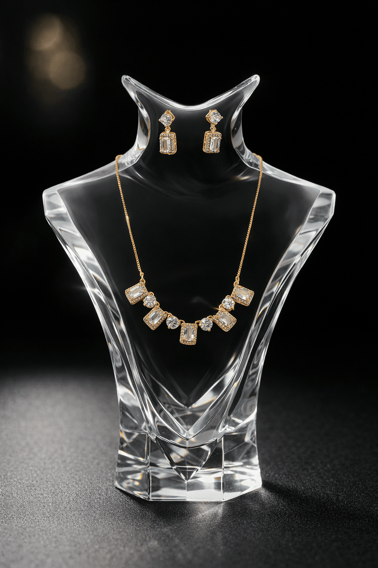 Jewelry set with necklace and earrings on a clear crystal stand against a black background