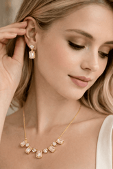 Woman wearing a gold necklace and earrings, close-up of face and jewelry.