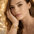 Woman wearing a gold bracelet with a blurred golden background