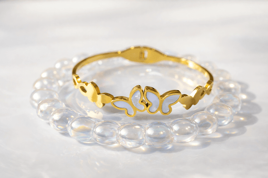 Gold bracelet with butterfly design on a white background