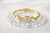 Gold bracelet with butterfly design on a white background