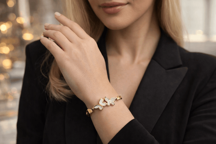 Woman wearing a gold bracelet with butterfly charms against a blurred background