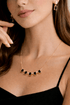 Close-up of a woman wearing a gold necklace with black gemstones and matching earrings.
