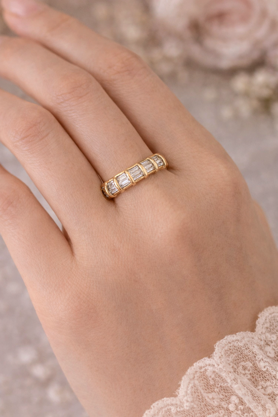 Gold ring with diamonds on a hand against a soft floral background