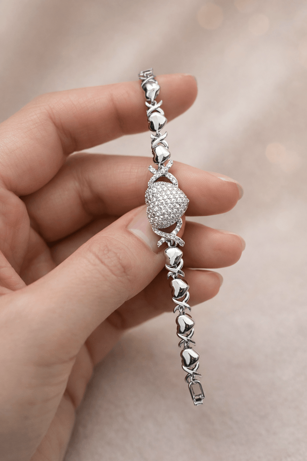 Silver bracelet with heart-shaped beads held in a hand against a soft background