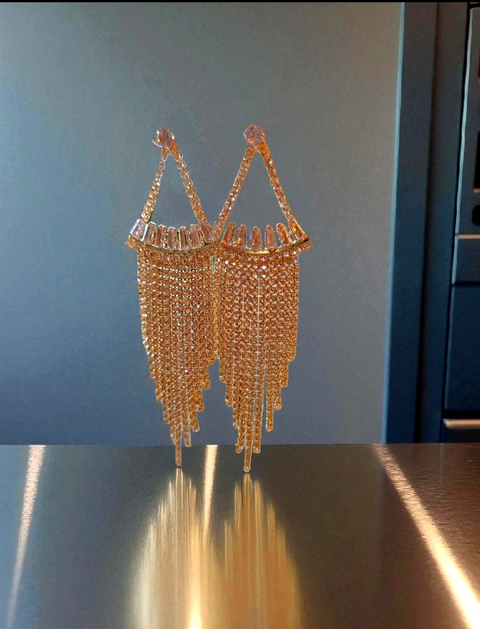 Gold beaded handbag on a reflective surface with a neutral background