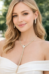 Woman wearing a necklace and earrings with a blurred green background