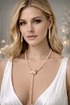 Woman wearing a rose gold necklace and earrings with a blurred light background