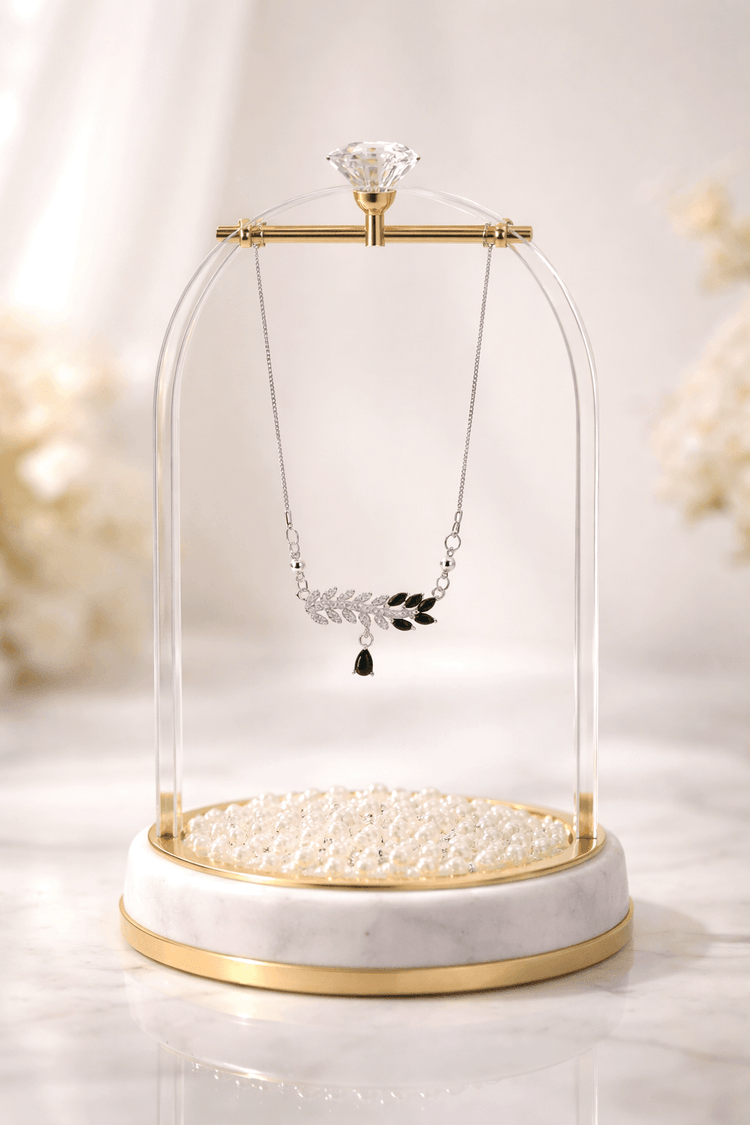 Necklace with pendant on a glass display case with pearls on a light background