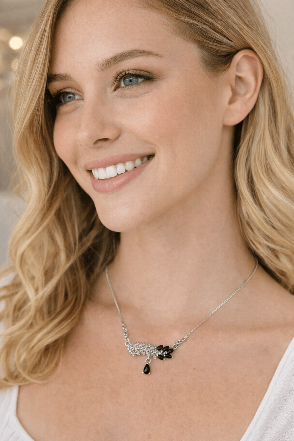 Woman wearing a necklace with a black pendant, smiling.