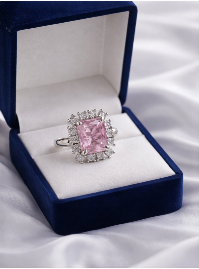 Pink diamond ring in a blue velvet box on a white fabric background