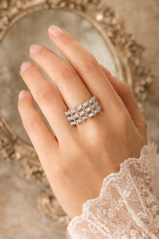 Hand wearing a diamond ring with an ornate mirror in the background
