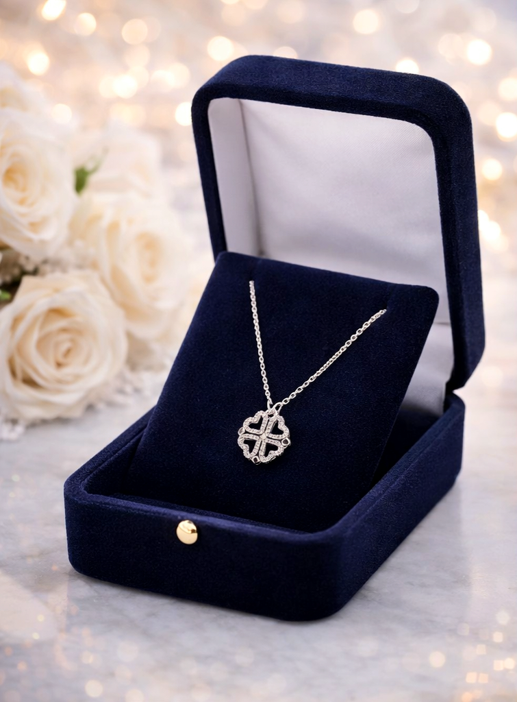 Silver necklace with a pendant in an open navy velvet jewelry box against a soft, blurred floral background.