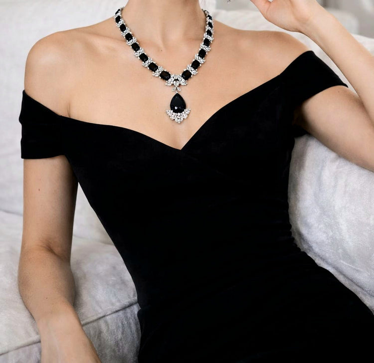 Person wearing a black off-shoulder dress and a black and white necklace.