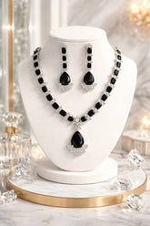Black and white jewelry set on a white mannequin bust with decorative background