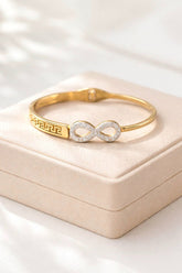 Gold bracelet with infinity symbol on a beige jewelry box