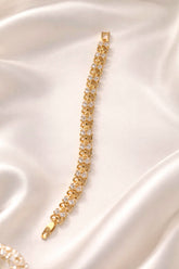 Gold bracelet with clear stones on a white satin background
