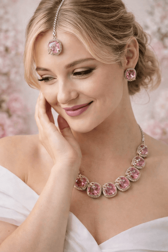 Woman wearing pink jewelry with a soft floral background