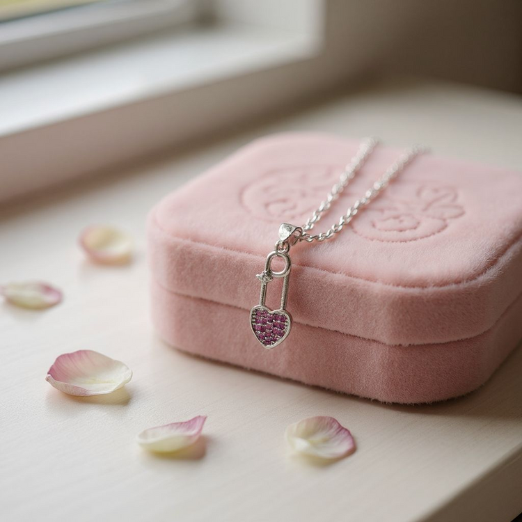 Necklace with a heart-shaped pendant on a pink jewelry box with flower petals around