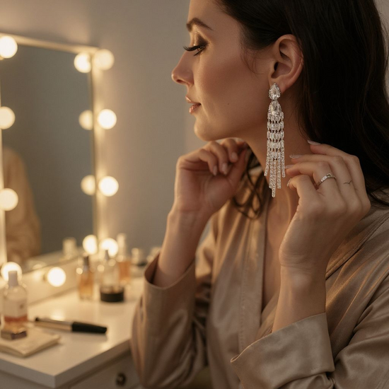 Woman adjusting earrings in front of a vanity mirror with lights.