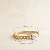 Gold bracelet with measurement details on a beige background