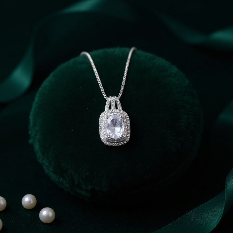 Silver necklace with a large diamond pendant on a dark green fabric background