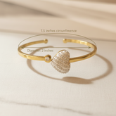 Gold bracelet with heart-shaped clasp on a beige fabric background