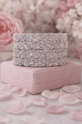 Decorative jewelry box with a sparkling bracelet on a pink surface with flowers in the background