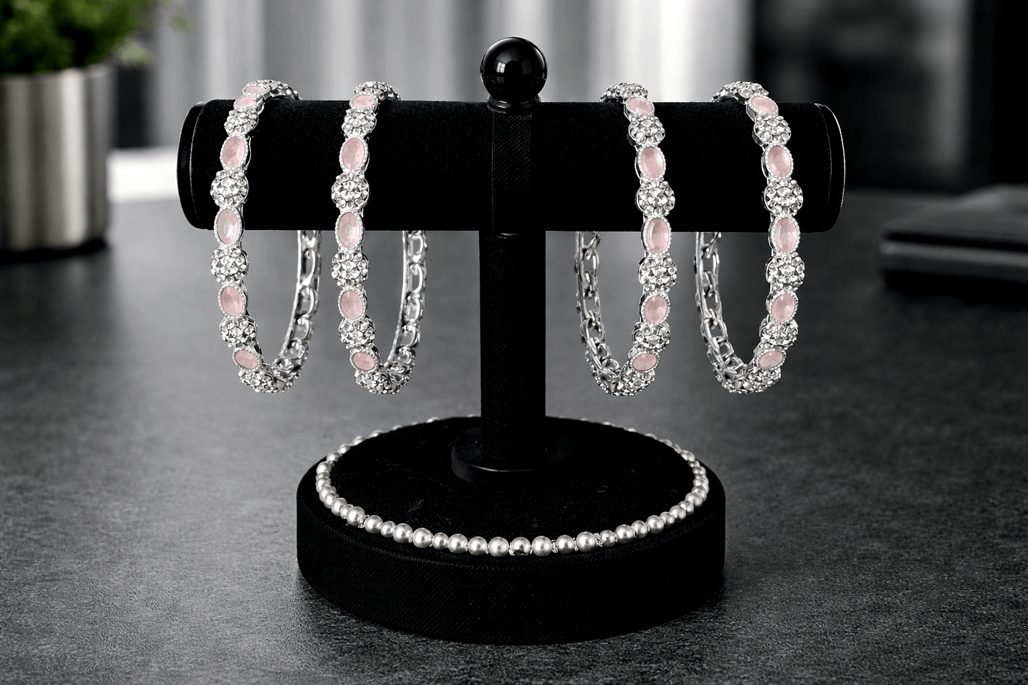 Set of pink beaded bracelets on a black stand with blurred background