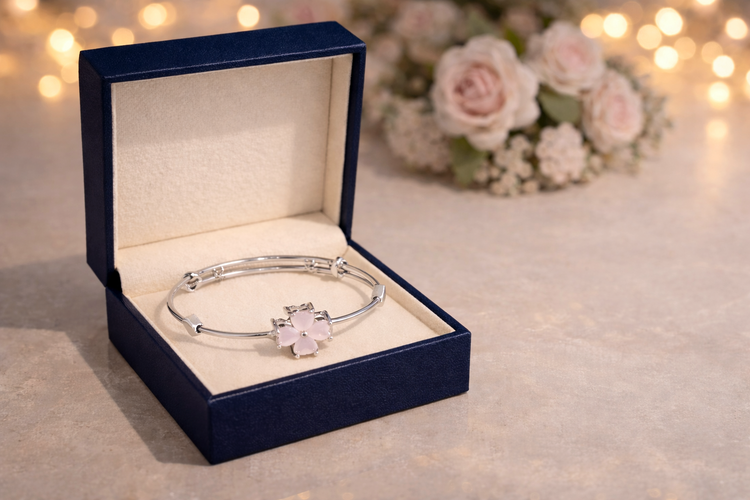 Silver bracelet with a floral design in an open blue jewelry box on a soft background.