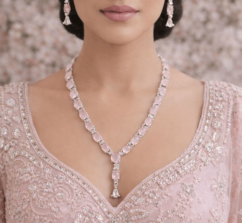 Woman wearing a pink necklace and earrings with a blurred floral background
