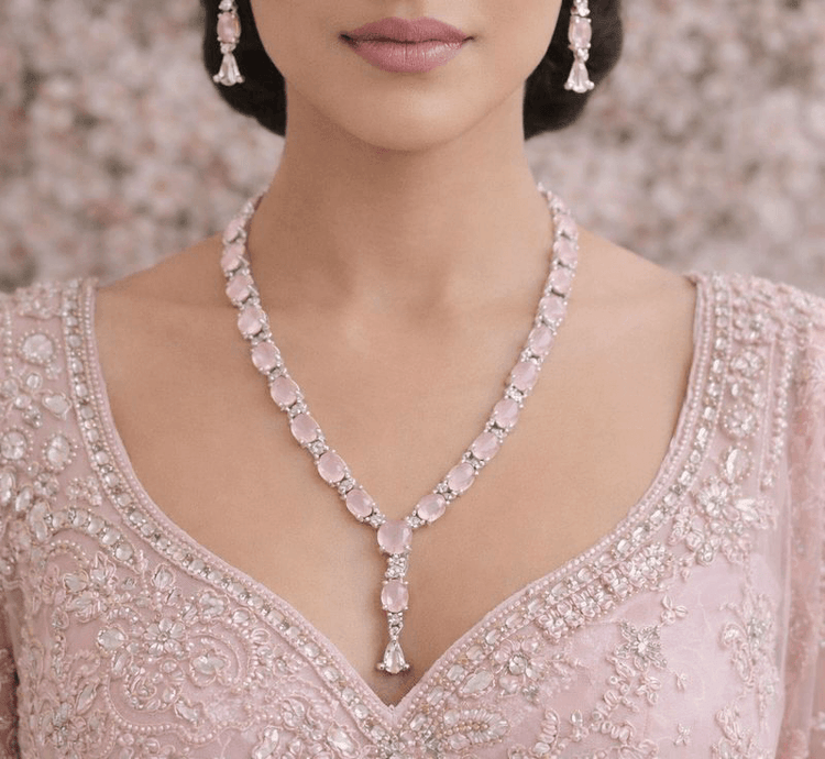 Woman wearing a pink necklace and earrings with a blurred floral background