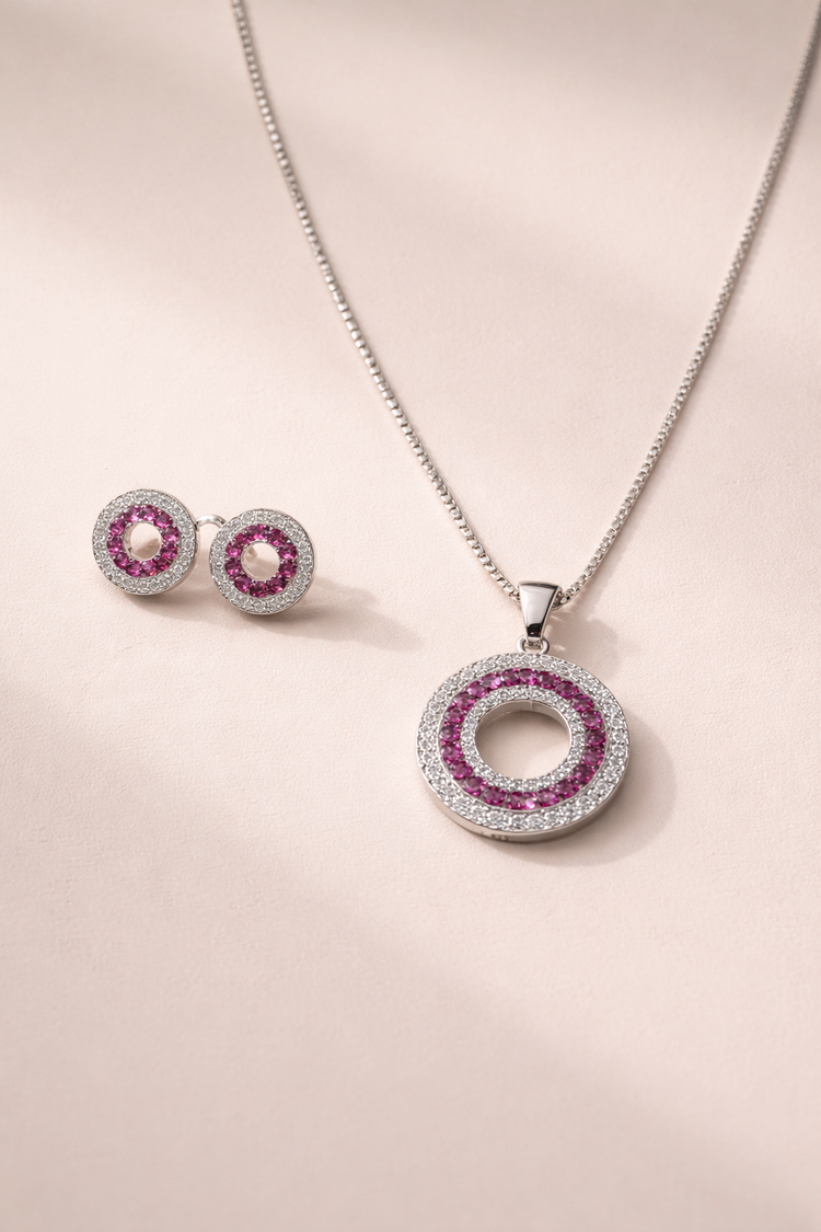 Jewelry set with circular pendant and earrings on a light pink background