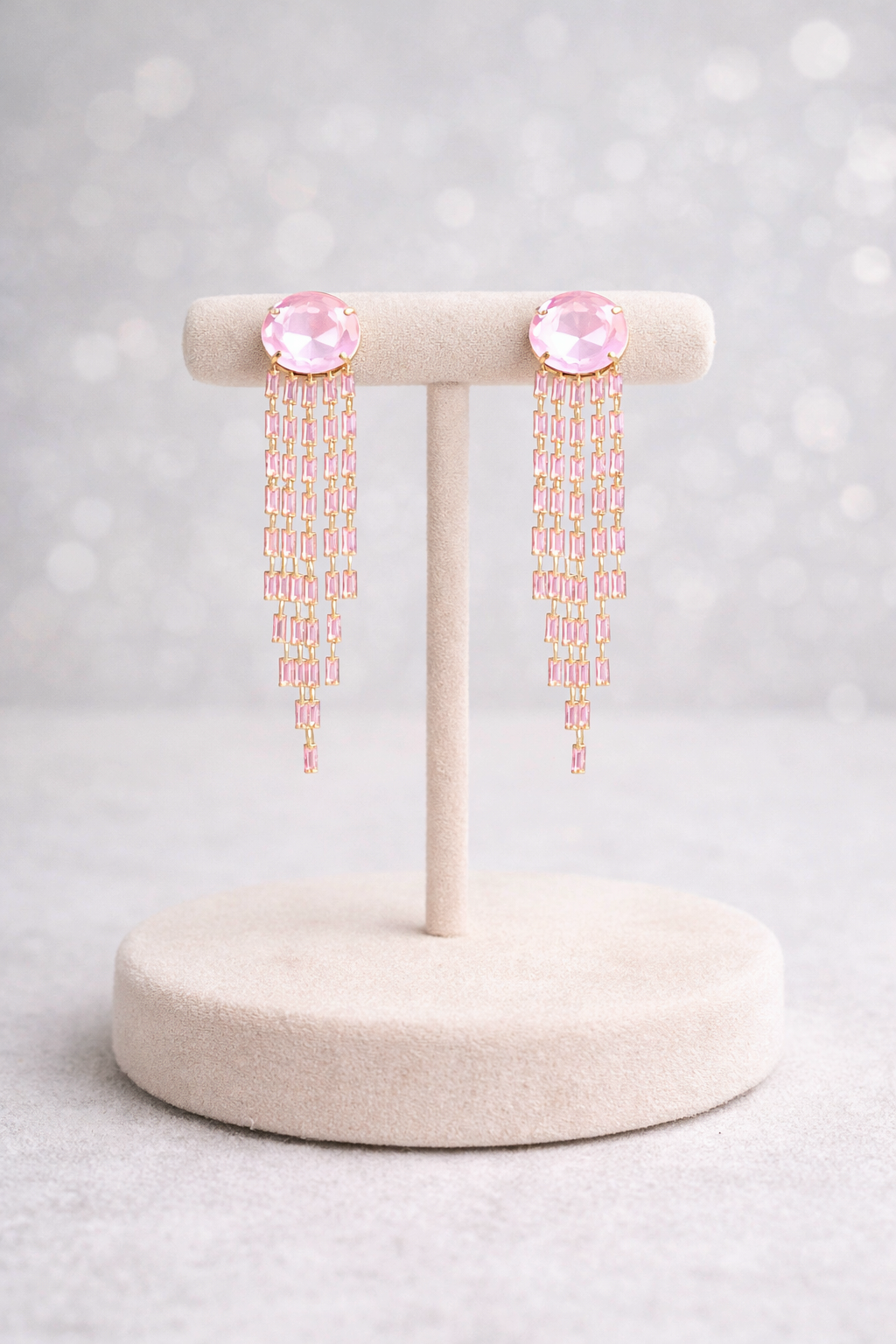Pair of pink earrings on a white stand with a light gray background