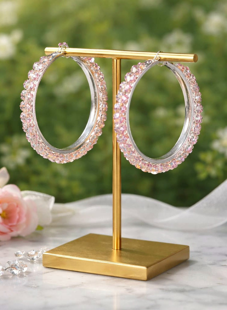 Pink hoop earrings on a gold stand with a floral background