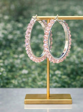 Pink beaded hoop earrings on a gold stand with a blurred green background