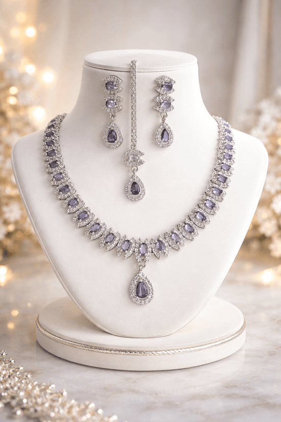 Purple gemstone necklace and earrings on a white mannequin bust with a soft blurred background.
